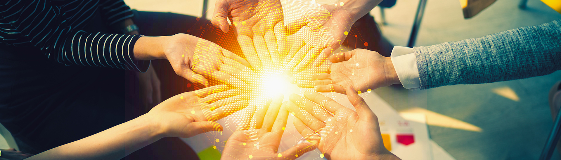 Several hands reaching for each other with a light in the middle of them